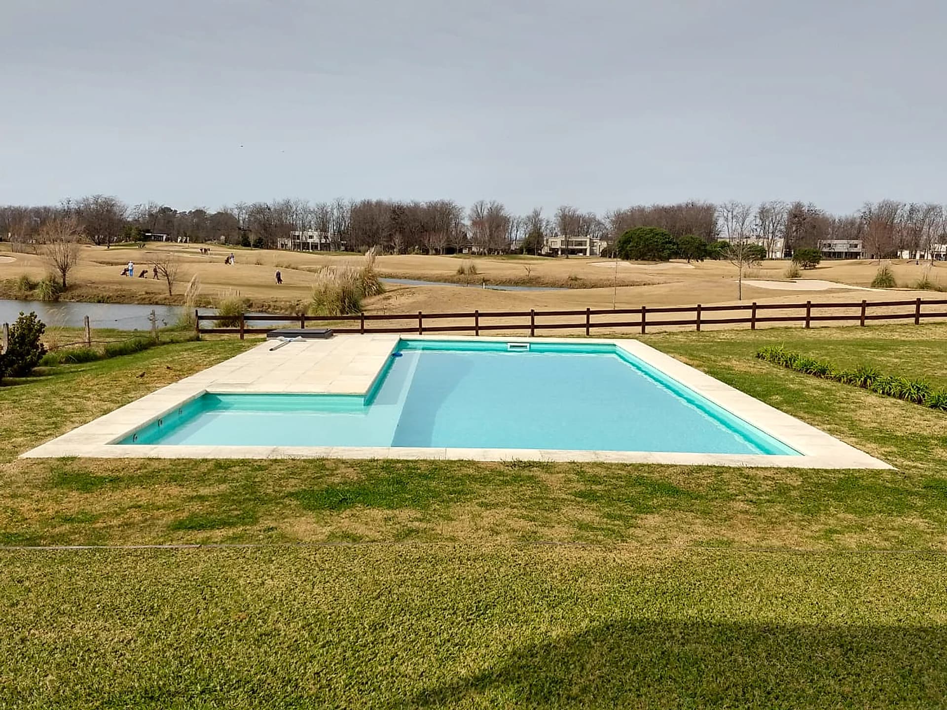 Piscina en country con playa húmeda frente a laguna y campo de golf