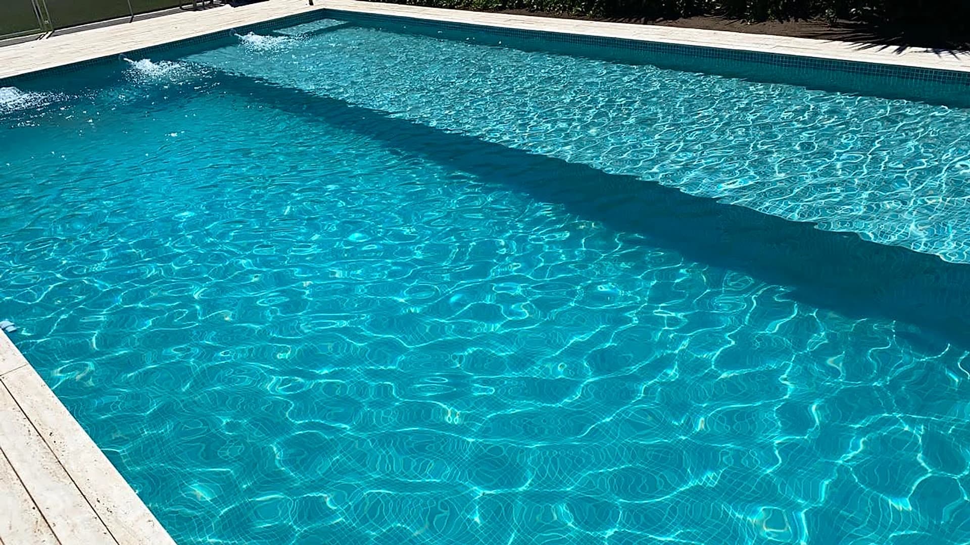 Piscina moderna con agua turquesa y borde travertino