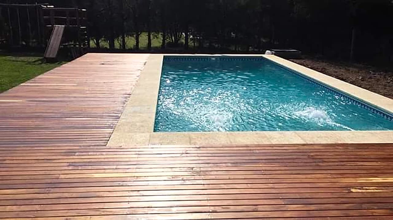 Piscina moderna con deck de madera natural y solárium