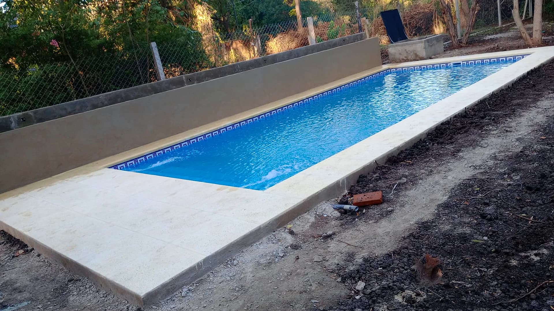 Piscina longitudinal moderna con solárium atérmico y guarda de venecitas